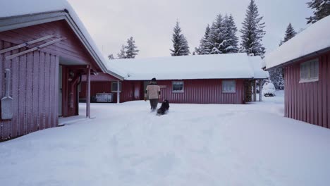 Hombre-Con-Su-Perro-Malamute-De-Alaska-Cerca-De-Cabañas-En-Indre-Fosen,-Noruega-Durante-El-Invierno---Ancho