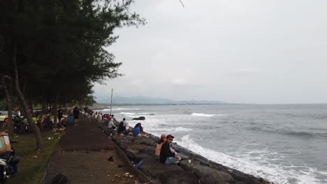 Bali-Beach-Masceti,-Personas-Y-Familias-Disfrutan-De-La-Tarde-En-Las-Olas-De-La-Costa-De-Arena-Negra-Y-El-Cielo-Azul-Plateado,-Gianyar,-Sudeste-De-Asia,-Pueblo-Local-Balinés,-Indonesia