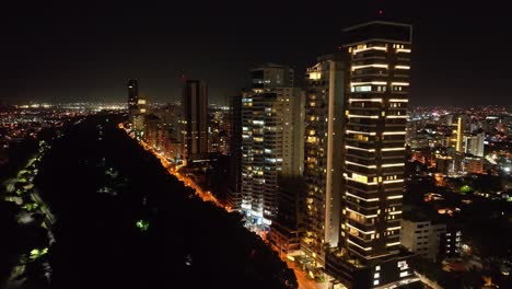 Skyscrapers-and-luxury-buildings-illuminated-along-Avenida-Anacaona-in-Santo-Domingo-city-at-night,-Dominican-Republic