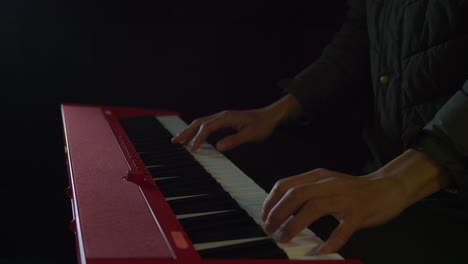 Statische-Nahaufnahme-Einer-Person,-Die-In-Einem-Schwach-Beleuchteten-Raum-Mit-Beiden-Händen-Auf-Einer-Klaviertastatur-Spielt