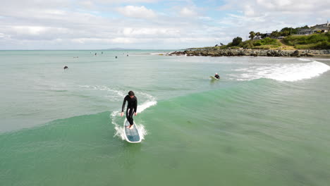Aerial,-man-in-wet-suit-surfing-on-wave-at-Riverton-Beach,-New-Zealand