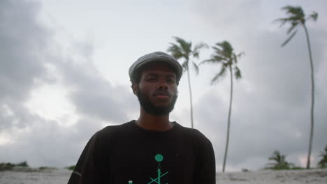 Mittlere-Aufnahme-Eines-Jungen-Schwarzen-Mannes-An-Einem-Exotischen-Strand-Mit-Palmen-Im-Hintergrund