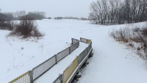 reverse-flying-aerial-of-a-cross-country-ski-bridge-in-a-park-like-setting-in-the-dead-of-winter