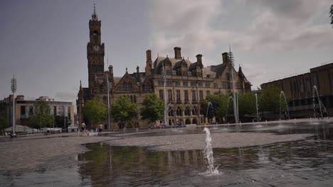 Kid-jumping-over-water-fountain-in-front-of-Bradford-town-hall-on-a-sunny-day