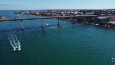 Aerial-view-of-speedboat-passing-with-bridge-in-background