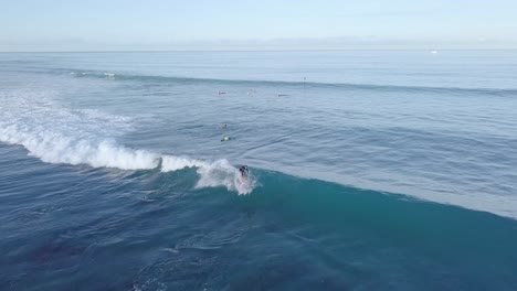 Surfer-shredding-a-wave-in-waikiki-hawaii-honolulu,-AERIAL-PULLBACK