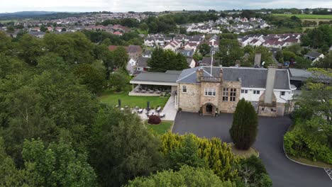 Aerial-video-on-Dalmeny-Park,-a-luxurious-Scottish-country-mansion-hotel-with-lush-gardens-and-views-of-and-nearby-population