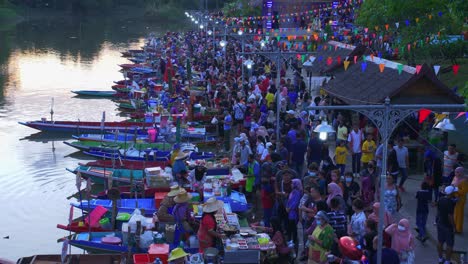 Overview-shot-over-busy-Khlong-Hae-Floating-Market-with-waterfront-community-selling-local-products-to-tourists-and-locals-in-Songkhla-province,-Thailand-after-sunset
