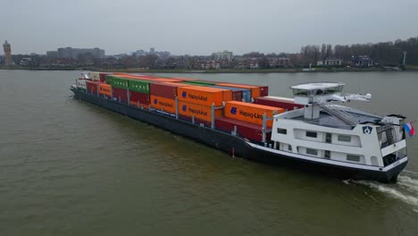 Aerial-View-Of-Port-Side-Of-Scaldis-Container-Ship-Travelling-Along-Oude-Maas-On-Overcast-Day-In-Dordrecht