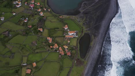 top-down-view-of-a-coastal-village-lush-green-landscape,-Fajã-de-Santo-Cristo,-São-Jorge-island,-the-Azores,-Portugal