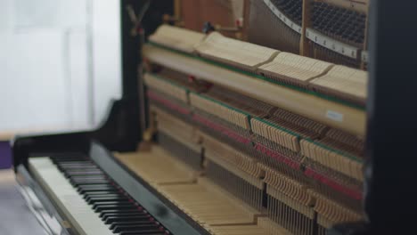 Inner-mechanism-of-an-open-wall-piano-on-a-pull-focus-shot