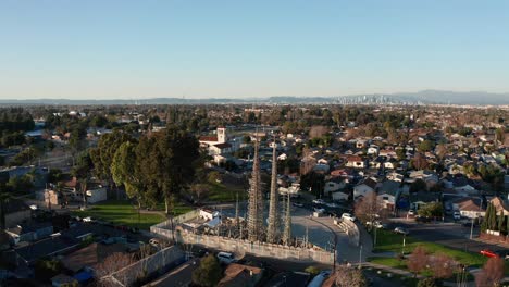 Aerial-panning-shot-of-the-Watts-Towers-with-downtown-Los-Angeles-in-the-distance