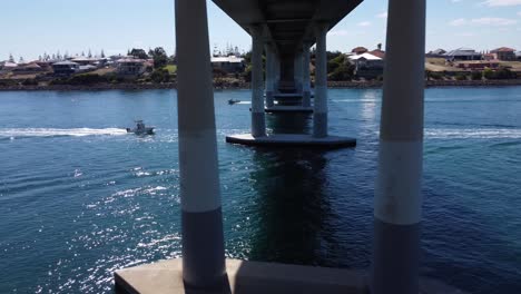 Aerial-track-of-speedboat-passing-under-bridge