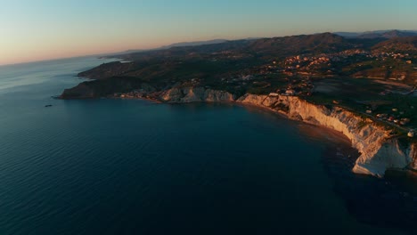 Aerial-shot-over-a-stunning-cliff-by-the-sea-on-the-island-of-Sicily,-Italy