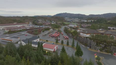 Collective-bus-terminal-in-Skogsvag-Oygarden-Norway---Aerial-looking-towards-terminal-and-Skogsvag-center-with-forest-in-foreground