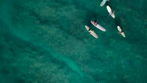 Surfers-in-waikiki-beach-honolulu-hawaii-waiting-patiently-for-a-wave-to-come,-AERIAL-TOP-DOWN-DOLLY-PAN