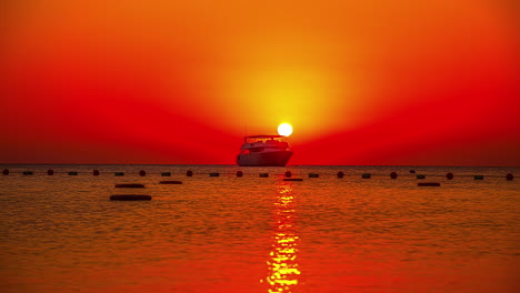 Silhouette-of-ship-on-sea-during-red-colored-sunset-at-horizon,-time-lapse