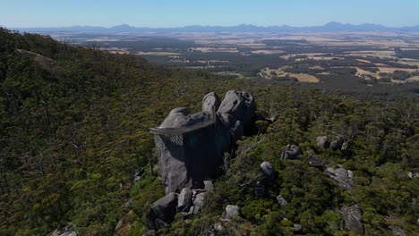 Aerial-orbit-of-boulder-lookout-in-Australian-bush,-mountains-in-background
