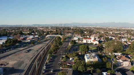 Wide-aerial-dolly-shot-from-the-LA-Metro-tracks-to-the-Watts-Towers-with-downtown-Los-Angeles-in-the-background
