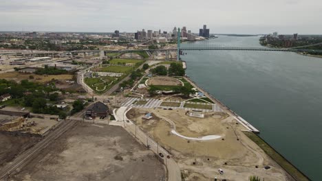 Riverside-park-under-construction-with-Ambassador-bridge-and-Detroit-skyline,-aerial-view