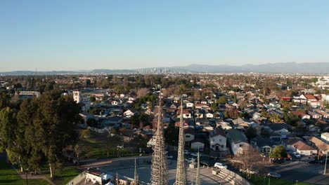 Reverse-pullback-aerial-shot-of-the-Watts-Towers-with-downtown-Los-Angeles-in-the-distance