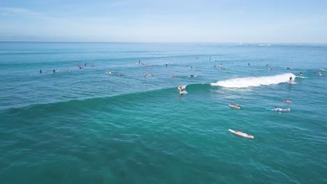 Surfers-ripping-waves-at-Waikiki-Beach-Honolulu-Hawaii,-AERIAL-DOLLY-BACK