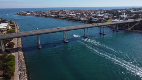 Aerial-view-of-speedboat-driving-underneath-bridge