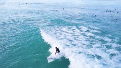 Männlicher-Surfer,-Der-Eine-Welle-Am-Waikiki-Beach-In-Honolulu-Hawaii-Mit-überfülltem-Wasser-Und-Blauem-Himmel-Schnitzt,-Luftlastwagenaufnahme