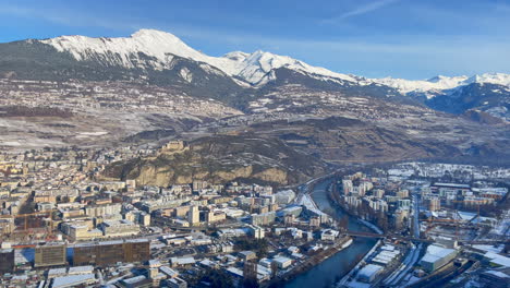 Helicopter-take-off-panning-shot-of-the-Swiss-city-of-Sion-in-the-snow-capped-Alps-on-a-sunny-winter-day