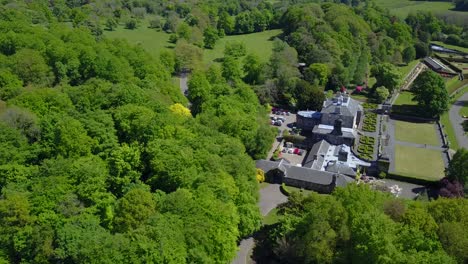 Aerial-pullback-view-over-pollock-house-famous-country-mansion-surrounded-by-vegetation-and-a-river-on-the-countryside-of-Glasgow