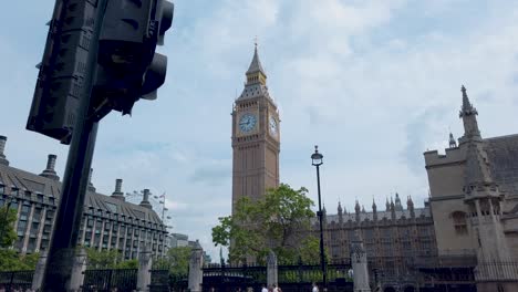 Walk-next-to-Big-Ben-with-the-Palace-of-Westminster-in-front,-people-walking