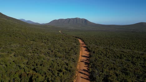 Aerial-shot-of-empty-red-dirt-road-with-moutain-in-distance-in-Australian-outback