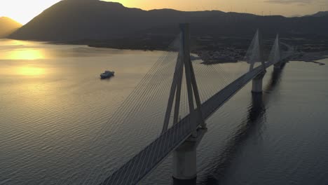 Aerial---Rio-Antirrio-bridge-in-Greece-at-sunset-with-boat-passing-by-in-the-background---Shot-on-DJI-Inspire-2-X7-RAW