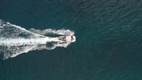 Small-white-boat-speeding-across-ocean-aerial-straight-down-view