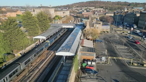 Train-parked-in-train-station-with-passengers-leaving-the-train-with-platform-and-carpark-UK