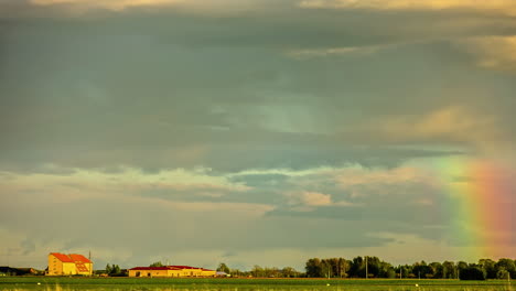 Coole-Zeitraffer-Eines-Regenbogens-Und-Wolken,-Die-Sich-Am-Himmel-über-Einer-Straße-Auf-Einem-Bauernhof-Bewegen
