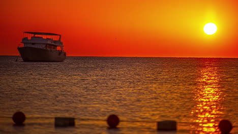 Moored-boat-at-sunset-over-sea-with-orange-colored-sky-in-background