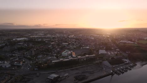 Drohnenflug-über-Den-Hafen-Von-Dundalk,-Während-Die-Sonne-Hinter-Der-Stadt-Untergeht