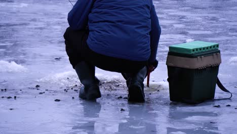 Medium-shot-of-the-fisherman-removes-the-scoop-from-the-hole-extra-snow-and-ice-for-winter-fishing