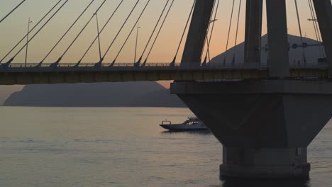 Aerial---Boat-passing-by-behind-Rio-Antirrio-bridge-in-Greece-at-dusk---Shot-on-DJI-Inspire-2-X7-50mm-RAW