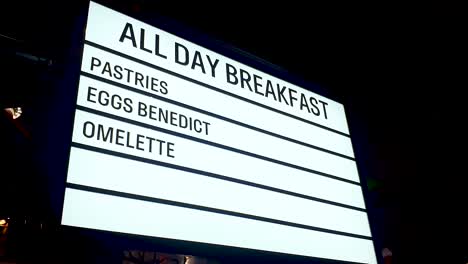 All-day-breakfast,-pastries,-eggs-benedict-and-omelette-neon-LED-sign-surrounded-by-flashing-fairy-lights-at-diner-restaurant-cafe