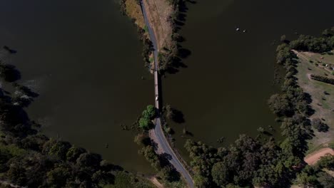 small-bridge-over-a-lake-in-a-rural-setting,-aerial-straight-down
