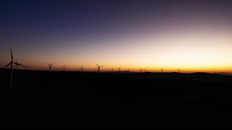 Time-lapse-aerial-view-of-wind-farm-as-sunrises-over-horizon-at-dawn,-Israel