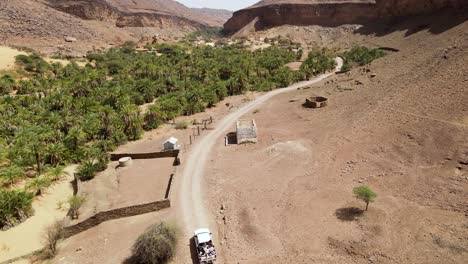 Car-Driving-in-Terjit-Oasis-Village-in-Mauritania-Sahara-Desert,-Aerial-Drone-Tilt-up