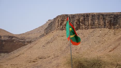Mauritania-Flag-Waves-by-Atar-Mountain-Cliffs-in-Terjit-Oasis,-Static
