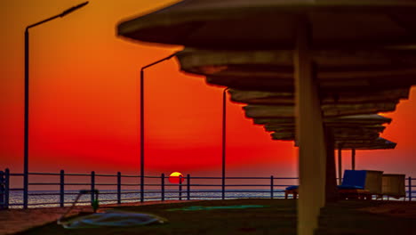 Sun-disappearing-at-horizon-and-beautiful-orange-sky-over-sea-at-sunset,-Day-to-night-time-lapse