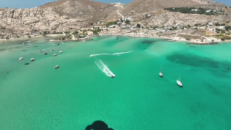 Boats-driving-fast-off-the-beach-in-Paros,-Greece