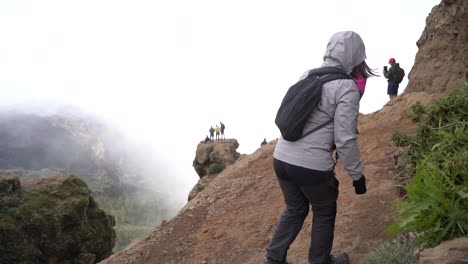 Las-Palmas-de-Gran-Canaria,-Spain---January-24,-2023:-Hiking-group-ascending-to-Roque-Nublo-duroing-a-misty-morning-in-Gran-Canary-Island,-Spain