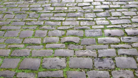 Walking-along-Vicar's-Close,-the-oldest-inhabited-street-in-Europe,-top-down-view-of-historic-cobbled-street-of-cobblestones-in-Wells,-Somerset-England