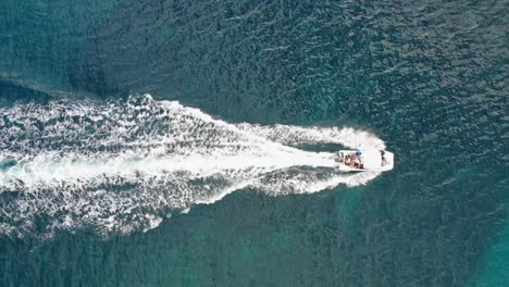 High-angle-aerial-motorboat-creating-whitewash-on-turquoise-ocean